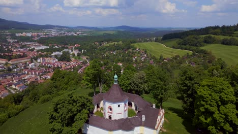Magic-aerial-top-view-flight-Round-Chapel-on-mountain-hill,-Krumlov-Czech-Republic-Summer-2023