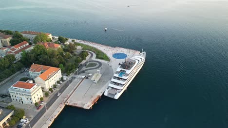 Luxury-cruise-ship-docked-near-the-light-installation-filled-by-sun-Greetings-to-the-sun-and-Sea-Organ,-an-instrument-played-by-waves-in-Zadar,-Croatia