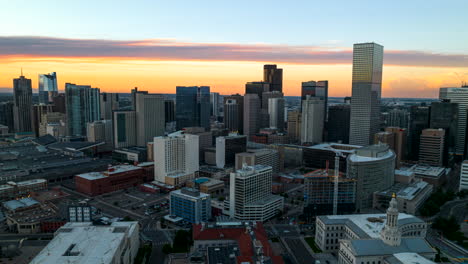 Denver-city-skyline-aerial-hyperlapse-at-sunset-twilight,-vibrant-yellow-horizon