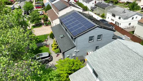 Luftflug-Zeigt-Modernes-Haus-Mit-Installierten-Sonnenkollektoren-Auf-Dem-Dach-An-Sonnigen-Tagen-In-Der-Amerikanischen-Nachbarschaft