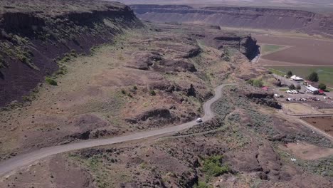 Flight-follows-van-descending-into-coulee-formed-by-ice-age-floods,-WA