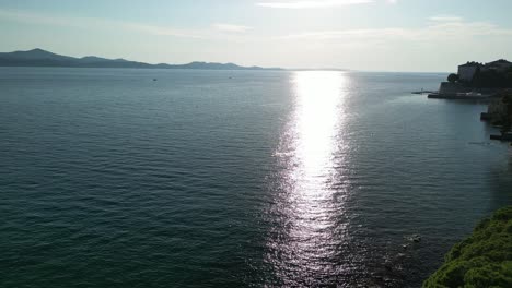 Sunny-blue-Adriatic-coast-in-Zadar,-Croatia-with-pool-and-diving-platform,-an-aerial-footage