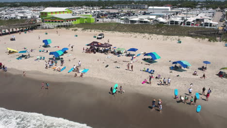 Drone-shot-of-surfing-event-on-the-beach-with-tents-set-up,-slowly-rotating