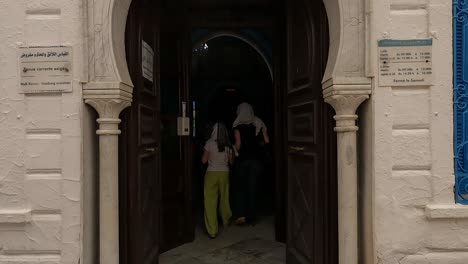 Vista-Posterior-De-Una-Mujer-Y-Una-Niña-Entrando-En-La-Sinagoga-Judía-Más-Antigua-De-África,-Djerba-En-Túnez.