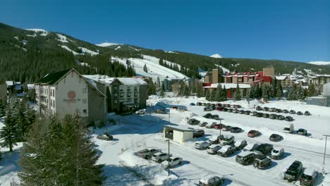 Drone-aerial-Copper-Mountain-winter-ski-snowboard-resort-Ikon-Pass-parking-lot-lodging-hotels-Colorado-early-morning-sunlight-fresh-snow-ski-lift-crowd-cinematic-dolly-upward-motion-4k