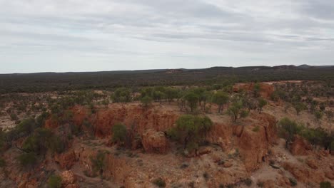 Drohne-Steigt-über-Einen-Seltsamen-Hügel-Auf-Und-Zeigt-Im-Hintergrund-Das-Zerklüftete-Australische-Buschland