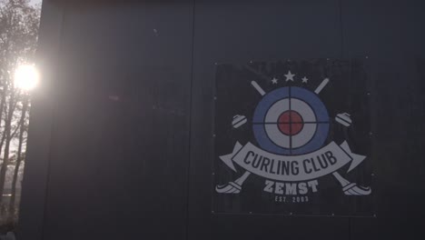 Logo-Des-Curlingclubs-Zemst-Auf-Einem-Gebäude-Mit-Sonnenschein-Flair