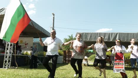 Man-leads-cheerful-dancers-and-waves-national-flag-at-cultural-festival