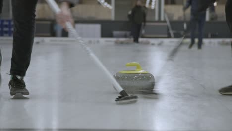 Zwei-Spieler-Fegen-über-Die-Eisdecke-Vor-Einem-Curlingstein