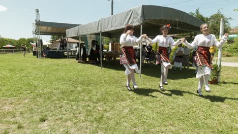 Young-ladies-in-costume-dance-happily-at-Bulgarian-summer-folk-festival