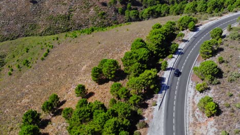 Drone-shot-of-a-car-pulling-over-from-a-road-in-the-hills-in-Andalusia,-Spain