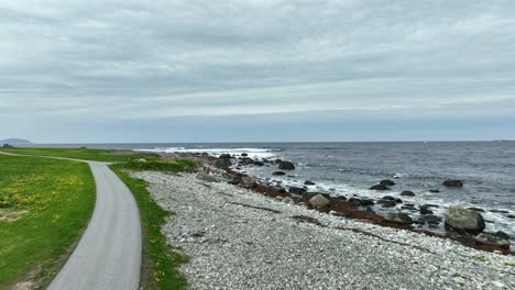 Coastal-road-near-Alnes-lighthouse---Following-narrow-road-before-flying-ahead-and-ascending-above-North-Sea-and-Atlantic-Ocean