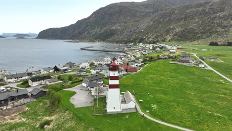 Beautiful-Alnes-lighthouse-outside-Alesund-Norway---Aerial-rotating-and-descending-around-lighthouse-before-revealing-ocean-and-coastal-landscape