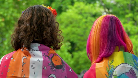 Girls-with-their-backs-turned,-covered-in-colorful-flags