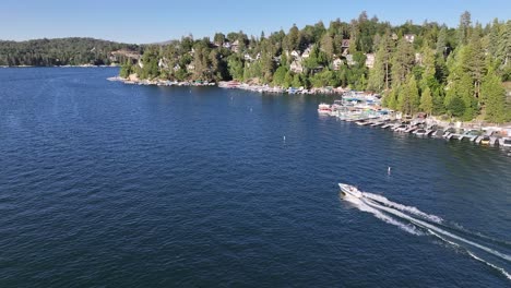 following-a-speed-boat-on-lake-arrowhead-california-with-a-view-of-lakeside-homes-and-docks-sunny-day-AERIAL-TRUCKING-PAN