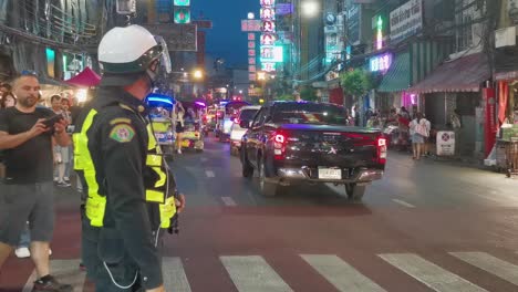 Thailändischer-Verkehrspolizist-Benutzt-Taschenlampe-Mit-Touristen,-Die-Die-Yaowarat-Road-In-Chinatown-überqueren