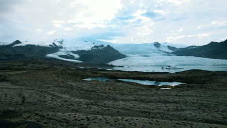 Iceberg-A-La-Deriva-En-La-Superficie-Del-Agua-Del-Glaciar,-Derretimiento-De-Los-Glaciares-Debido-Al-Calentamiento-Global,-Camión-Parado-En-Medio-De-La-Carretera-Islandesa-De-Campos-De-Lava,-Islandia,-Toma-Aérea