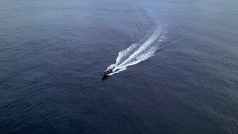 Aerial-view-of-fast-moving-whale-watching-boat-being-steered-in-azure-blue-ocean