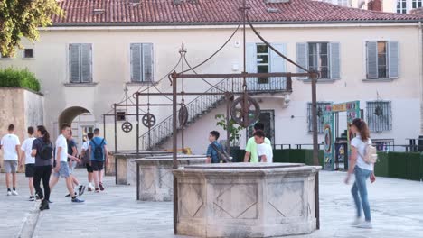 Un-Grupo-De-Adolescentes-En-Giras-Visitando-La-Plaza-De-Los-Cinco-Pozos-En-Zadar,-Croacia.