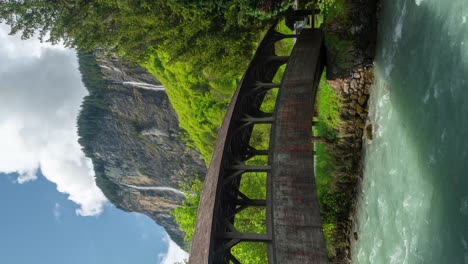 Vertikaler-4K-Zeitraffer,-Idyllisches-Dorf-In-Den-Schweizer-Alpen,-Holzsteg,-Fluss,-Wasserfälle-Und-Grüne-Landschaft-Im-Frühling