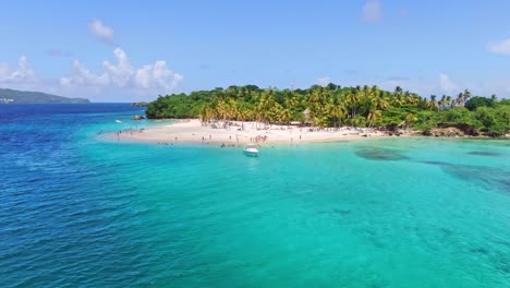 Aerial-orbiting-shot-of-many-tourist-on-luxury-island-with-tropical-palm-trees-and-turquoise-water---Cayo-Levantado,-Dominican-Republic