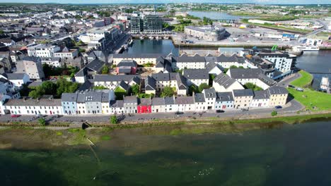 Backward-tilt-down-over-scenic-houses-and-dock-on-hot-day-in-Galway-Bay,-Ireland