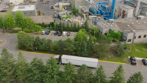 Aerial-Tracking-Shot-of-Loaded-Semi-Truck-Departing-Industrial-Factory