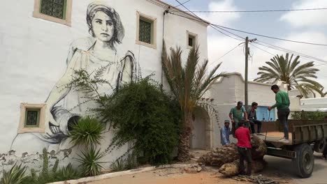 Männer-Versuchen,-Eine-Palme-Auf-Einen-Pickup-Am-Straßenkunststandort-Djerbahood-In-Tunesien-Zu-Laden