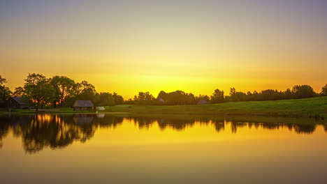 Golden-dawn-over-a-lakeside-cabin-in-the-countryside---sky-reflecting-off-the-water-time-lapse