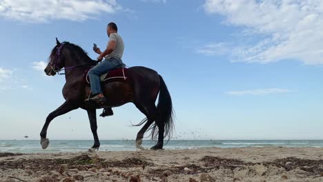Horseback-riders-by-beach-at-dusk.-Low-angle