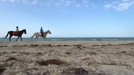Horse-riders-relaxing-horseback-riding-on-sandy-seashore