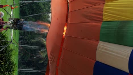 Vertikale-Zeitlupen-Nahaufnahme-Eines-Bunten-Und-Großen-Heißluftballons,-Der-Mit-Einem-Brenner-Mit-Gas-Und-Flammen-Für-Eine-Ballonfahrt-Auf-Bali,-Indonesien,-In-Ubud-Aufgeblasen-Wurde