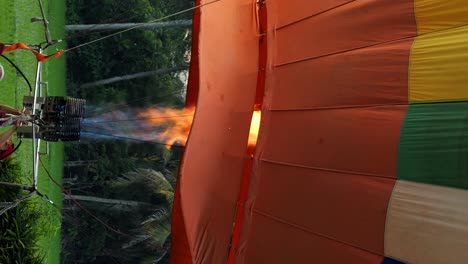 Vertical-slow-motion-close-up-shot-of-a-hot-air-balloon-being-inflated-with-a-burner-with-gas-and-flames-for-a-balloon-flight-in-bali-indonesia-in-ubud