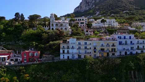 Wohngebäude-Auf-Einem-Hügel-Mit-Touristen,-Die-Am-Strand-Auf-Der-Insel-Capri-In-Italien-Ein-Sonnenbad-Nehmen