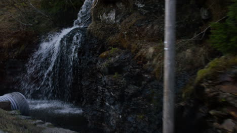 Slow-motion-dolly-shot-past-a-small-waterfall-on-a-cliff-face-in-Vestland,-Norway