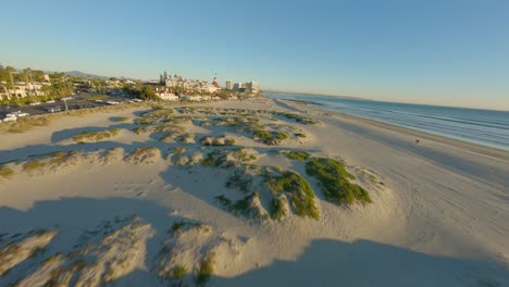 Aerial-FPV-shot-of-a-beach-landscape-during-sunset-near-hotel-resorts