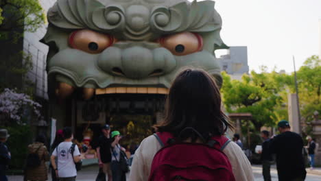 Toma-En-Cámara-Lenta-Siguiendo-A-Una-Mujer-Caminando-Hacia-Una-Estatua-Demoníaca-En-Osaka.