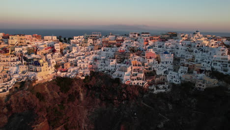 Luftaufnahme-Des-Dorfes-Auf-Roten-Felsen-Und-Klippen-Der-Griechischen-Insel-Santorini-Bei-Sonnenuntergang,-Drohnenaufnahme