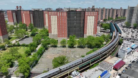 New-York-City-passenger-train-passing-tall-apartment-buildings-in-Coney-Island,-NYC