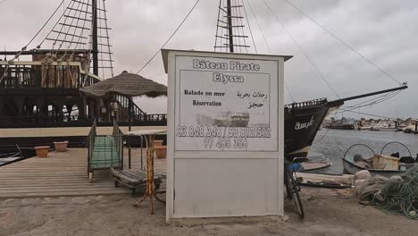 Djerba-port-with-fishermen-boats,-nets-and-touristic-pirate-galleon-ships,-first-part