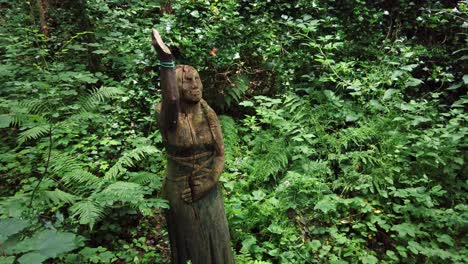 Decorative-carved-American-Indian-female-statue-among-wild-overgrown-woodland-forest-vegetation