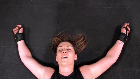 Mujer-Cansada-En-El-Suelo-Después-De-Un-Intenso-Ejercicio-En-El-Gimnasio