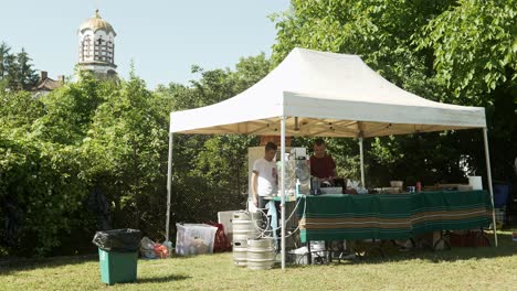 Un-Hombre-Saluda-Desde-Una-Carpa-De-Cerveza-Barbacoa-Lista-Para-Las-Multitudes-Del-Festival-De-Verano-Local