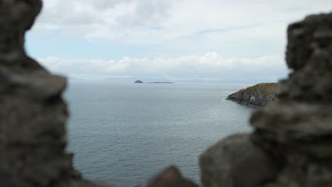 Handheld-push-in-past-rocky-foreground-overlooking-islands-off-coast-of-Scotland