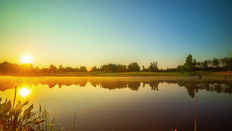 Sunrise-time-lapse-on-a-misty-morning-over-a-lake-with-the-sky-reflecting-off-the-glassy-water