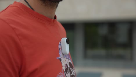 Hombre-Conectando-Insta360-Go-3-Al-Colgante-Magnético-Debajo-De-Una-Camiseta-Naranja