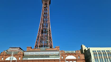 Looking-up-at-Blackpool-tower-pan-down-to-comedy-street-art-at-the-bottom-of-seaside-town-promenade