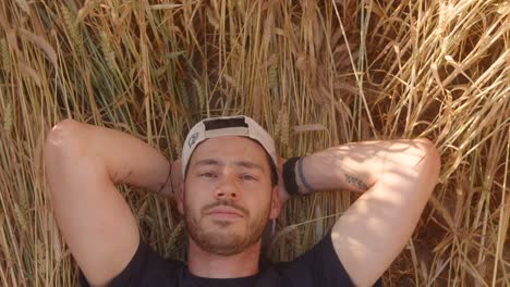 Portrait-of-a-man-in-a-cap-lying-relaxed-on-wheat-field-ground