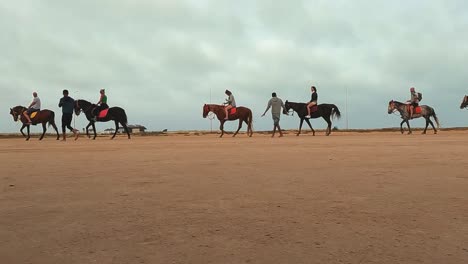 Seitenansicht-Einer-Pferdekarawane-Mit-Touristen-Zu-Pferd,-Die-Die-Wüste-Djerba-In-Tunesien-Durchqueren