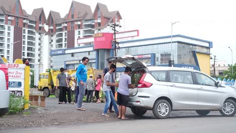 wide-angle-view-of-young-children-buying-tree-saplings-from-street-market-and-stuffing-them-into-their-car-deck-before-the-monsoon-season